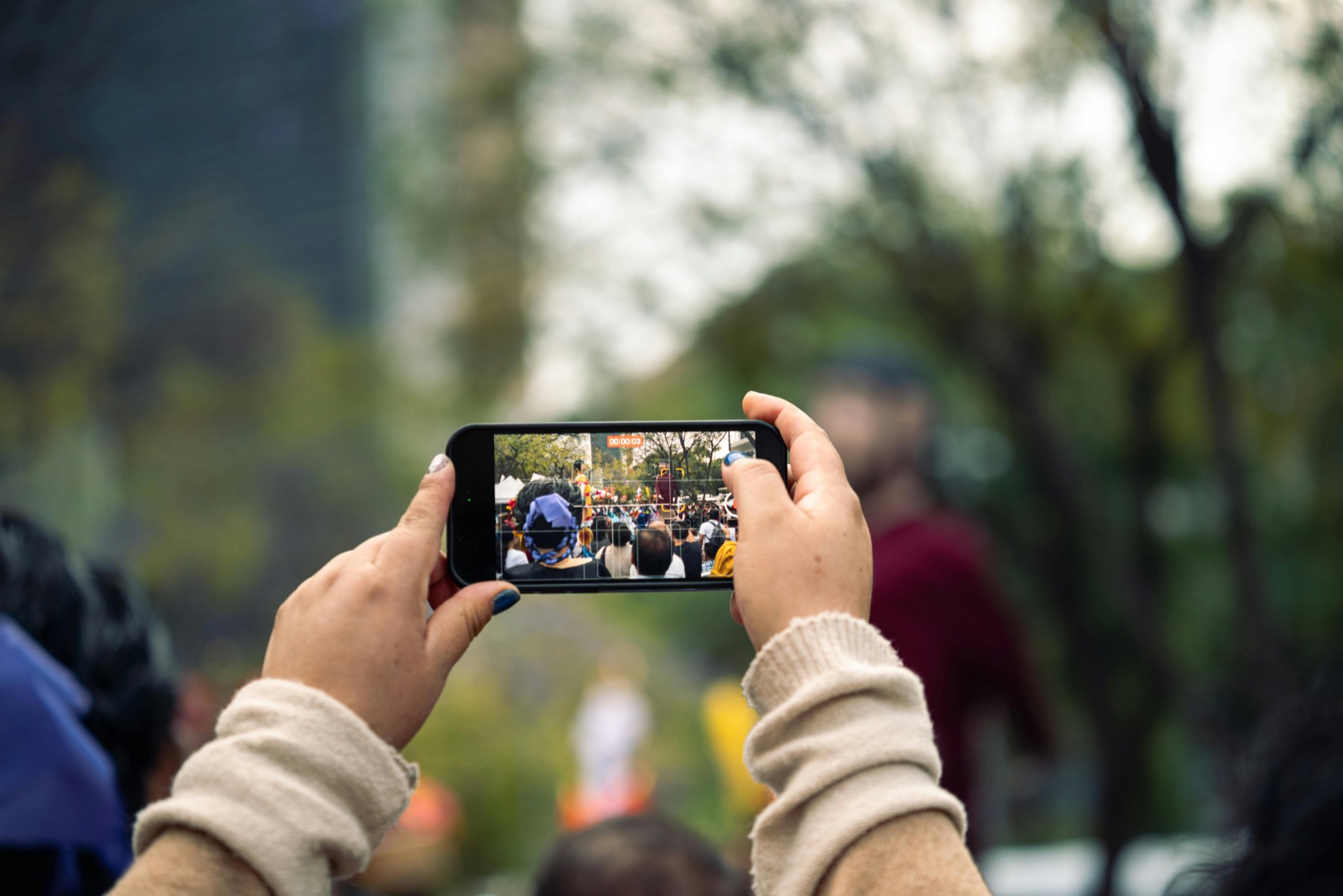 Personne filmant un événement sur smartphone dans un espace public